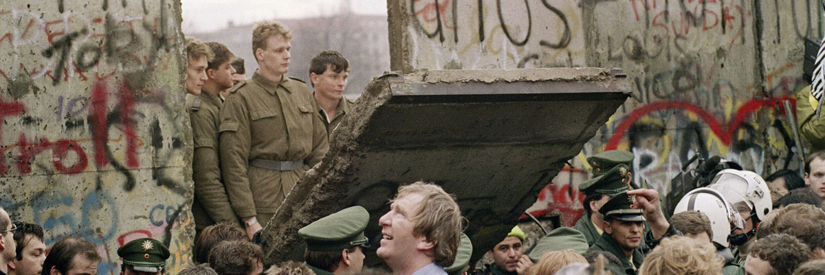 Imagen: Alemanes del oeste se amontonan para ver cómo cae el muro ante la mirada de los soldados de Alemania del Este. (Gerard Malie/AFP/Getty Images).
